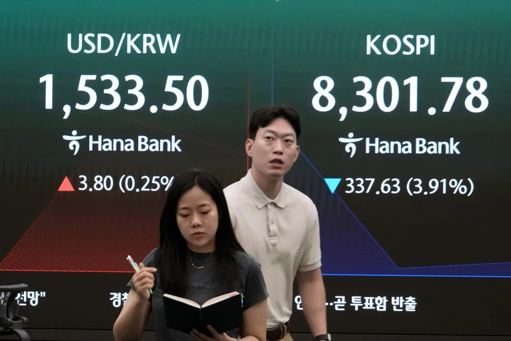 นักเทรดสกุลเงินกำลังเดินผ่านหน้าจอที่แสดงดัชนีตลาดหลักทรัพย์เกาหลี (Korea Composite Stock Price Index) และอัตราแลกเปลี่ยนเงินดอลลาร์สหรัฐฯ ต่อวอนเกาหลีใต้ ที่สำนักงานใหญ่ของ Hana Bank ในกรุงโซล เมื่อวันที่ 5 มิถุนายน
