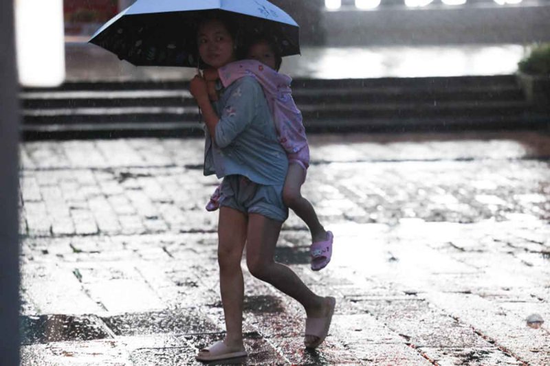 ภาพผู้คนกางร่มเดินท่ามกลางฝนที่ตกหนักขึ้นก่อนไต้ฝุ่นบาหวีจะมาถึงที่นครเวินโจว มณฑลเจ้อเจียง ประเทศจีน วันที่ 11 กรกฎาคม 2569