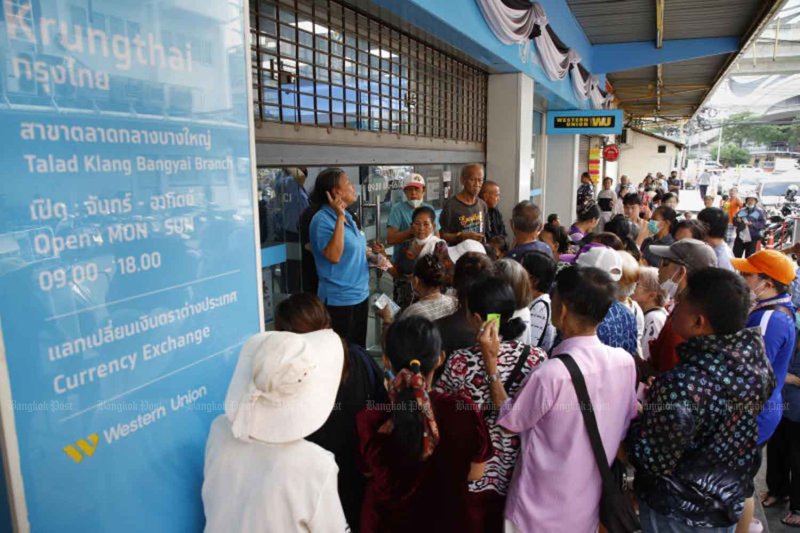 ฝูงชนรวมตัวกันที่หน้าธนาคารกรุงไทย สาขาตลาดบางใหญ่ จังหวัดนนทบุรี เพื่อขอความช่วยเหลือในการลงทะเบียนบัตรสวัสดิการแห่งรัฐรอบใหม่เมื่อเดือนมิถุนายน