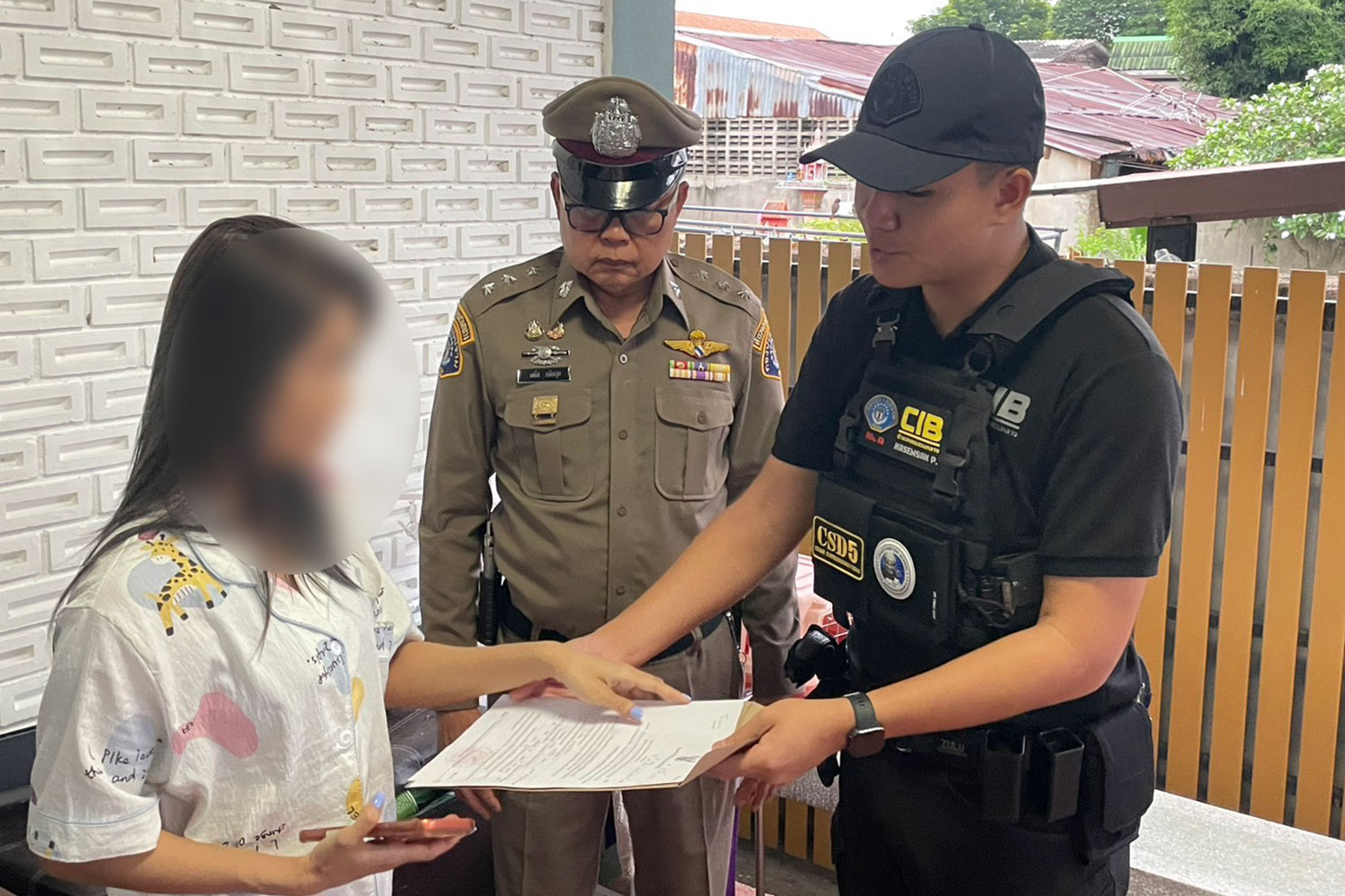ตำรวจไทยแสดงหมายจับต่อหญิงสาวที่ถูกออกหมายจับในข้อหาเกี่ยวข้องกับการหลอกลงทุนออนไลน์ (ภาพโดย Wassayos Ngamkham)