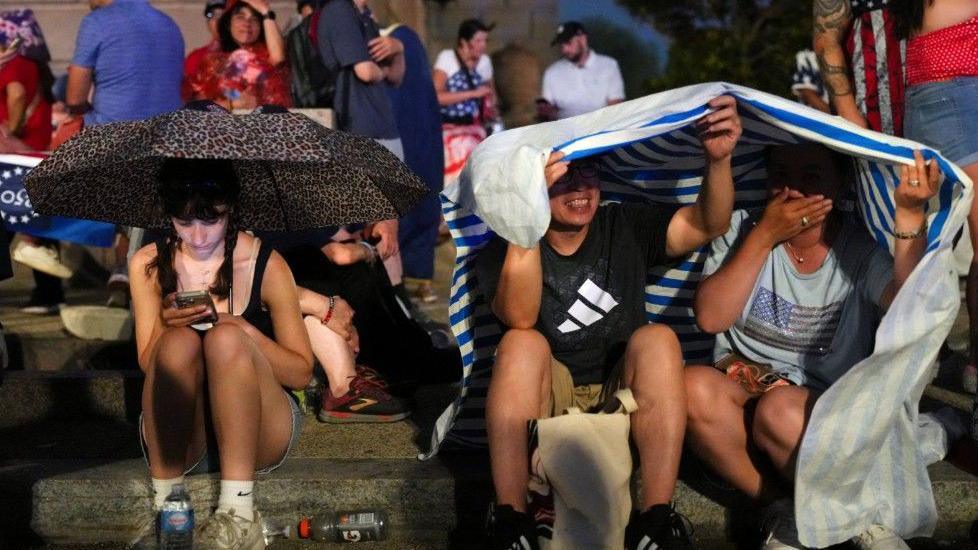 ผู้คนหลบฝนท่ามกลางพายุฝนก่อนการชุมนุมเนื่องในวันชาติ 4 กรกฎาคม ซึ่งจะมีประธานาธิบดีโดนัลด์ ทรัมป์ เข้าร่วม เพื่อเฉลิมฉลองวันครบรอบ 250 ปีเอกราชของสหรัฐฯ ในกรุงวอชิงตัน ดี.ซี. สหรัฐฯ วันที่ 4 กรกฎาคม 2026