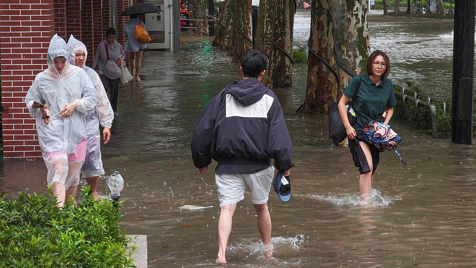 ชาวบ้านเดินลุยน้ำท่วมขังบนถนนในเซี่ยงไฮ้