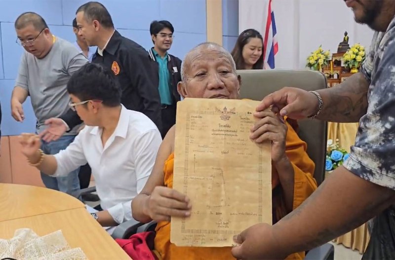 พระครูอดุลยสารนิติเทศ เจ้าอาวาสวัดป่าอดุลยาราม จังหวัดขอนแก่น แสดงโฉนดที่ดินที่ได้รับบริจาคแก่นเจ้าหน้าที่เมื่อวันศุกร์ (ภาพ: จักรพันธ์ นาทันรี)