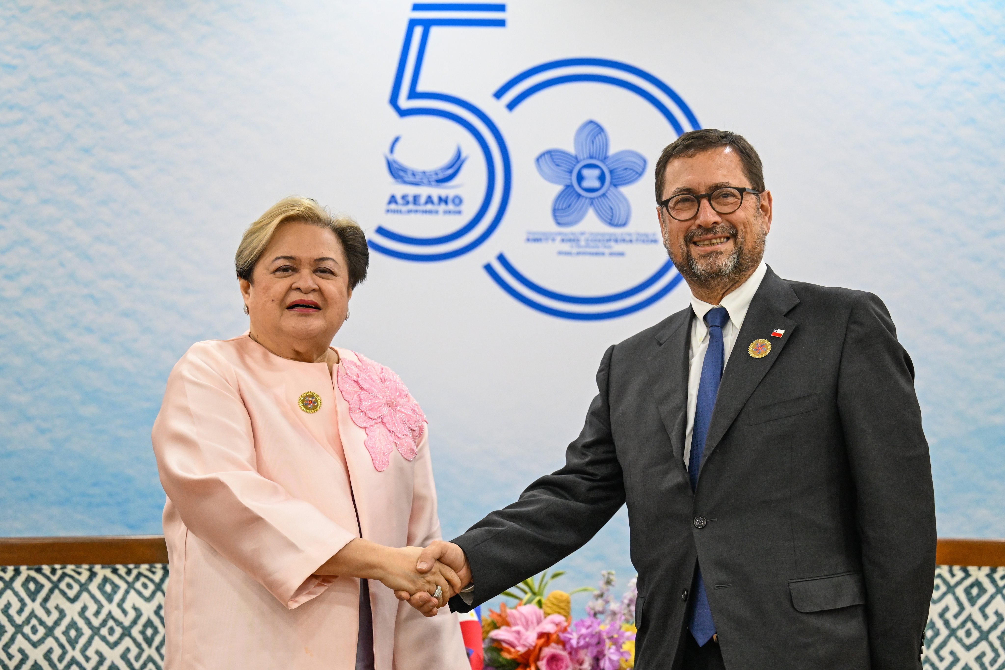 รัฐมนตรีต่างประเทศฟิลิปปินส์ มาเรีย เทเรซา ลาซาโร (ซ้าย) จับมือกับรัฐมนตรีต่างประเทศชิลี ฟรานซิสโก เปเรซ แมคเคนนา ระหว่างการประชุมนอกรอบการประชุมรัฐมนตรีต่างประเทศอาเซียนในกรุงเมโทรมะนิลาเมื่อเดือนที่แล้ว