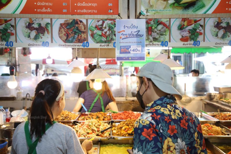 ผู้บริโภคกำลังเลือกซื้ออาหารที่ตลาดบางกะปิ เพื่อตัดสินใจว่าจะสั่งอะไรดี จากผลสำรวจของสำนักงานนโยบายและยุทธศาสตร์การค้า (สนค.) พบว่าชาวไทยส่วนใหญ่ที่เข้าร่วมโครงการร่วมจ่าย "คนละครึ่ง เฟสพลัส (60/40)" ใช้สิทธิ์เพื่อซื้ออาหารสำเร็จรูปและสินค้าจำเป็นในครัวเรือน (ภาพ: วรุธ หิรัญเทพ)