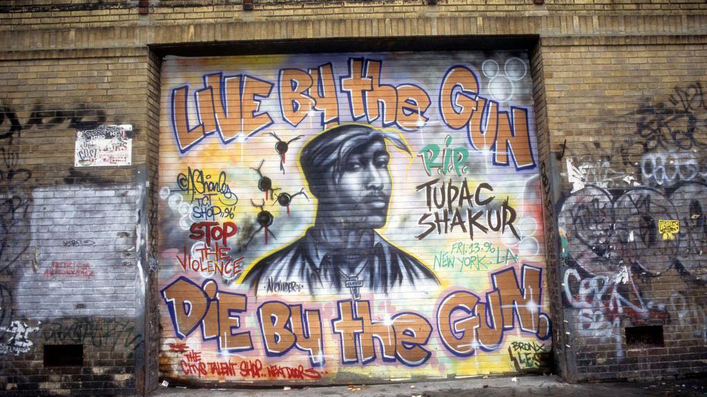ภาพจิตรกรรมฝาผนังของทูพัคแสดงใบหน้าของเขา และวลี: Live by the gun die by the gun