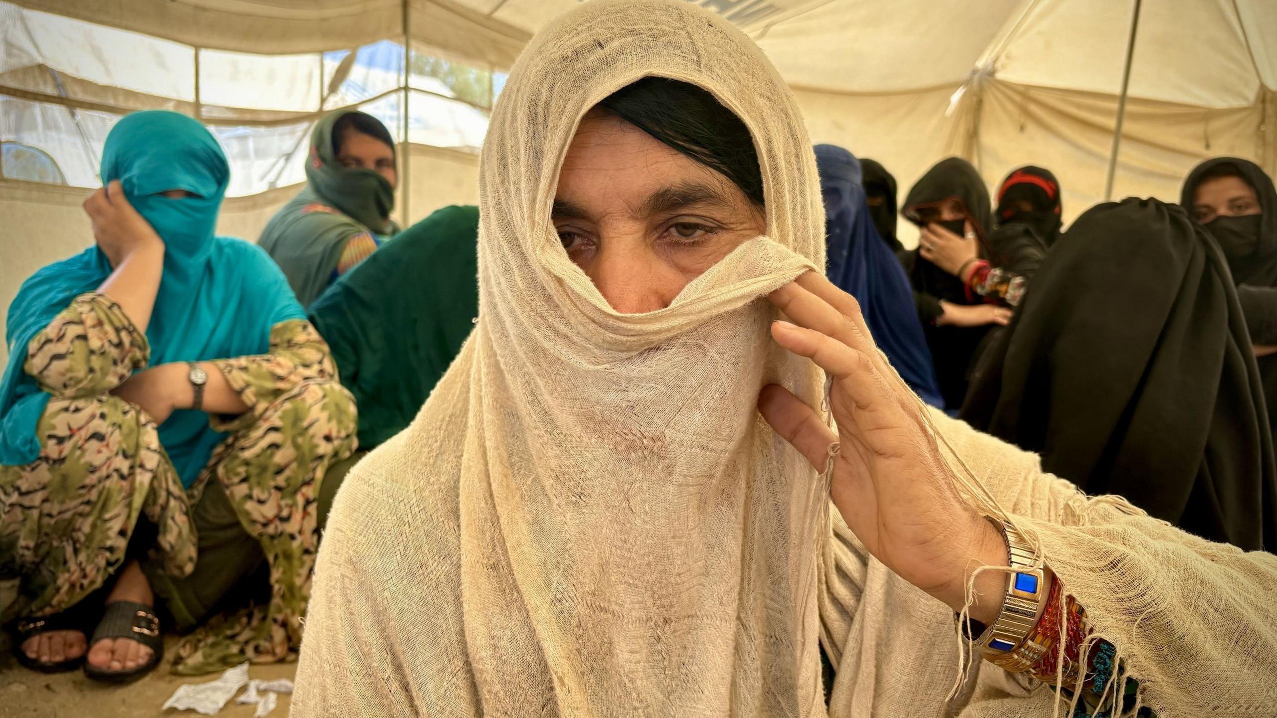 ซารินา ชาวอัฟกันที่กลับมาถึงประเทศ กำลังใช้ผ้าคลุมหน้าปิดบังใบหน้าบางส่วนขณะหันหน้าเข้าหากล้องภายในเต็นท์กับคนอื่นๆ