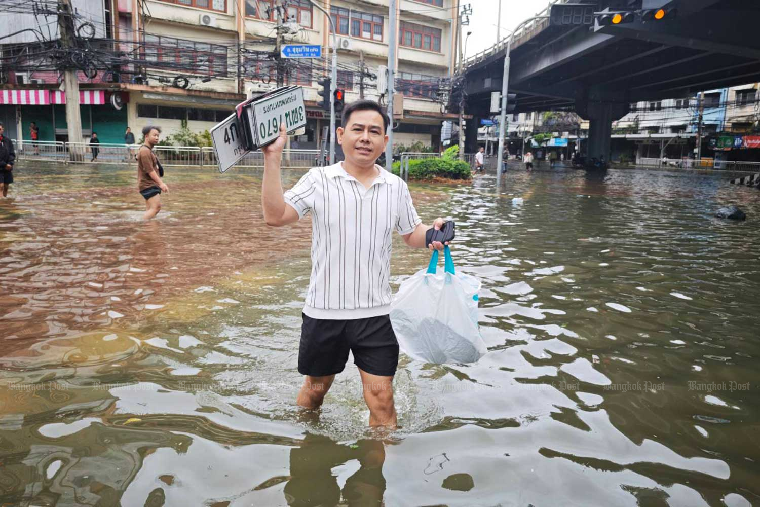 ชายคนหนึ่งกำลังรวบรวมป้ายทะเบียนรถเพื่อให้เจ้าของมารับคืนในภายหลัง ที่สี่แยกคลองตัน