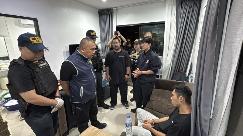 ตำรวจจับกุมผู้ต้องสงสัยที่นั่งอยู่ทางขวา ณ บ้านพักในเขตมีนบุรี กรุงเทพฯ คืนวันจันทร์ (ภาพถ่ายโดยตำรวจ)