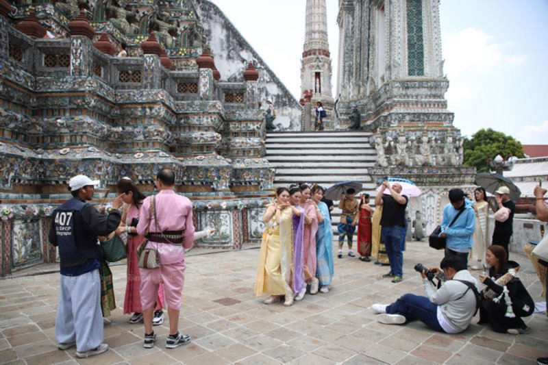 นักท่องเที่ยวในชุดไทยเช่าจากร้านค้าโพสท่าถ่ายรูปที่วัดอรุณฯ ในกรุงเทพฯ เมื่อวันที่ 27 เมษายน