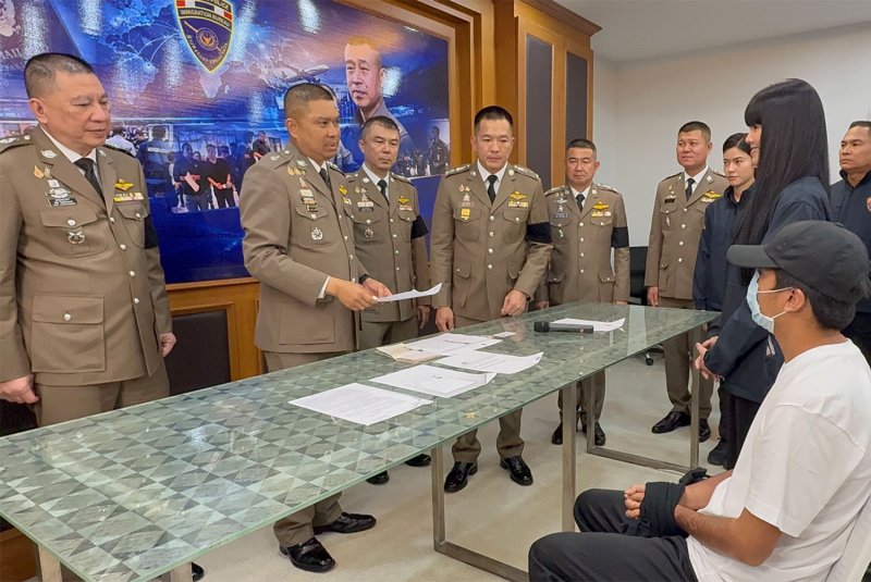 พล.ต.ท.นพศิลป์ พูลสวัสดิ์ (ที่สองจากซ้าย) ผู้บัญชาการสำนักงานตรวจคนเข้าเมือง สอบปากคำผู้ต้องหาสัญชาติต่างชาติคนหนึ่งจากทั้งหมดสองคน โดยมีล่ามช่วยแปลระหว่างการแถลงข่าวเมื่อวันพฤหัสบดี (ภาพโดย วัสโยส งามขำ)