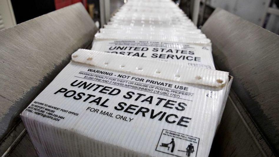 ภาพกองถาดแบนของบริการไปรษณีย์สหรัฐฯ (USPS) บนสายพานลำเลียง