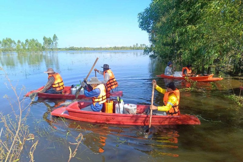 เรือบรรทุกเสบียงแล่นผ่านทุ่งนาที่ถูกน้ำท่วมในจังหวัดปราจีนบุรีเมื่อวันพุธ