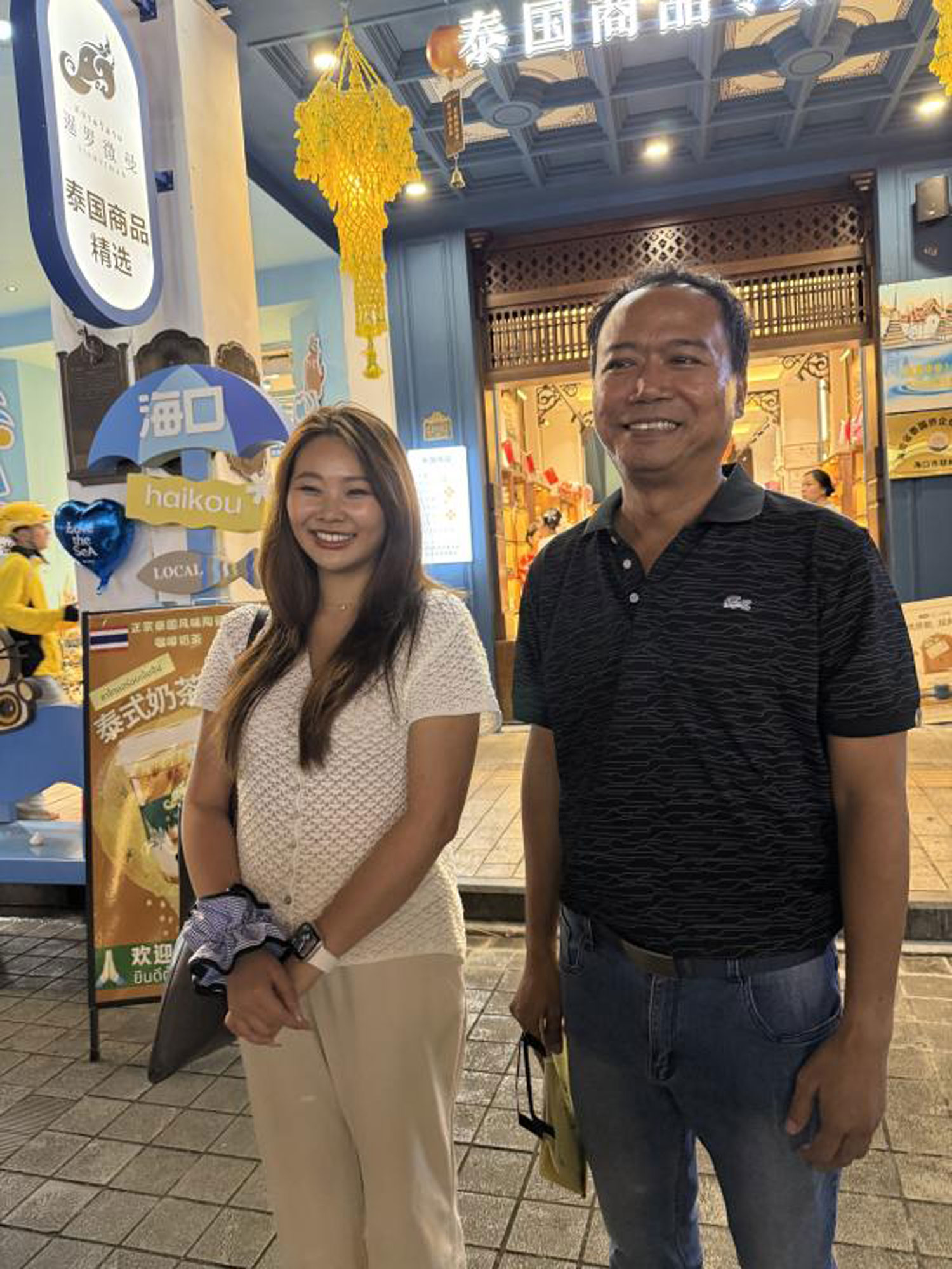 นักธุรกิจชาวไทยสองคนถ่ายรูปหน้าสยามวิมาน ร้านค้าปลีกสินค้าไทยบนถนนเก่าฉีโหลว (ภาพ: อนุชา เจริญโป)